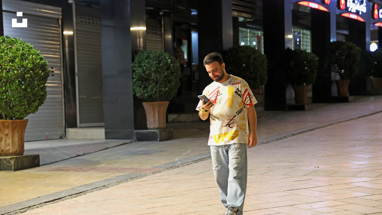 A person walking at night while looking at a phone, illustrating a dream about texting someone with no reply