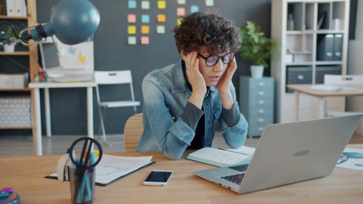 Person stressed at a laptop, symbolizing a dream about AI taking your job and work anxiety